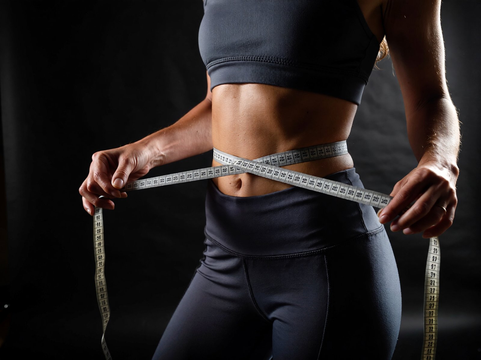 Gustavo_Denuncio_faça_uma_mulher_emagrecendo,_com_fundo_escuro_e_uma_fita_métrica_2f0e421f-53a6-450f-a90c-95e6889daf18